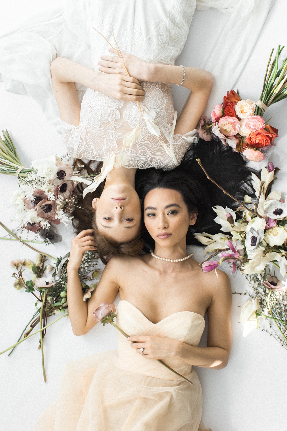 flatlay mariage luxe avec maries et leurs robes entourées de fleurs