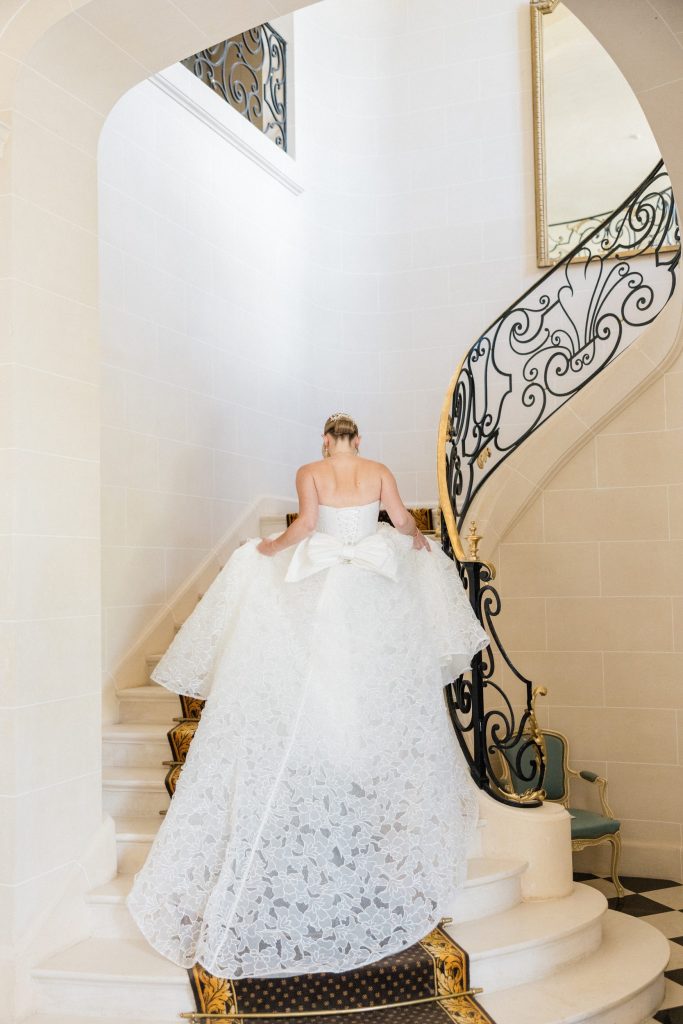 Elegant bride walking up the grand staircase at a French château wedding