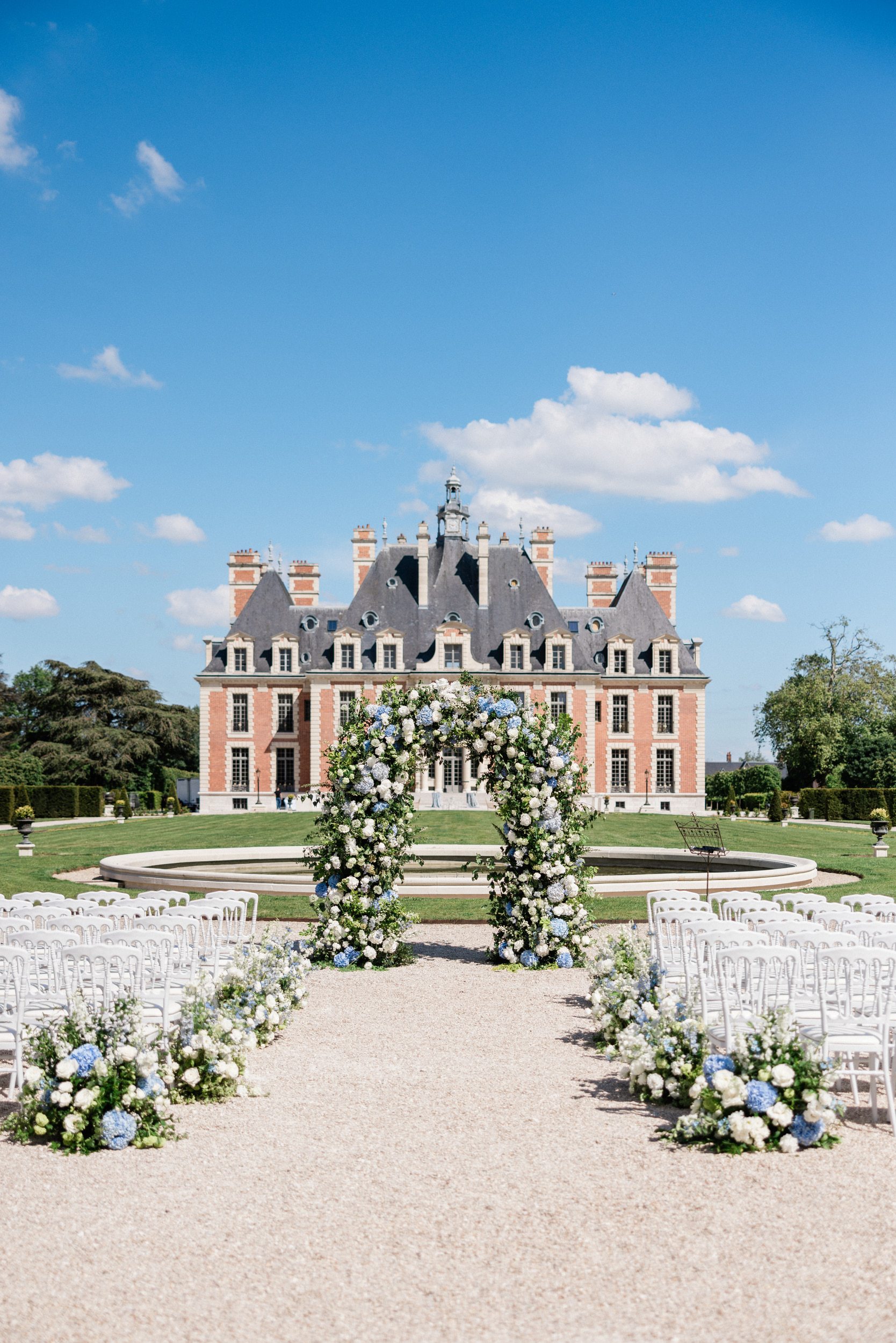 Wedding ceremony surrounded by blue and sage floral arrangements